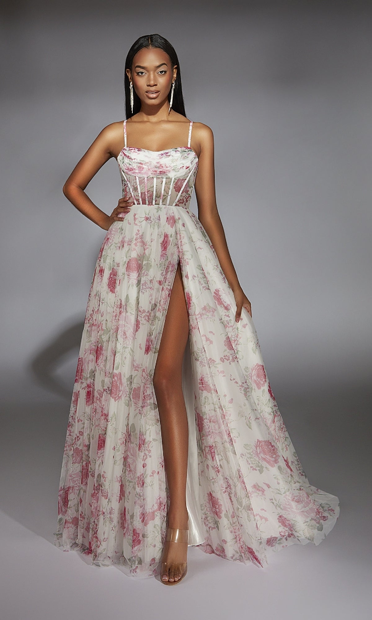 A woman models the Alyce 61752 long prom dress in white and pink, featuring spaghetti straps, a cowl neckline, corset bodice, high leg slit, and printed design, posed against a gray background.